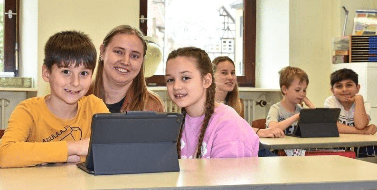 Grundschüler lernen mit ihrer Lehrerin mit der Anwendung Tutoring for All lesen